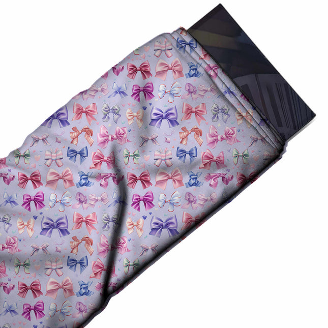 Flat fabric swatch: small-scale rows of satin-look bows in pink, magenta, periwinkle blue, design Design No_4462, Clothwala