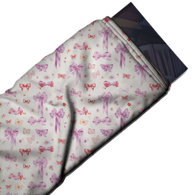 Flat fabric swatch: small-scale scattered print of lilac and pink satin bows with long, design Design No_4456, Clothwala